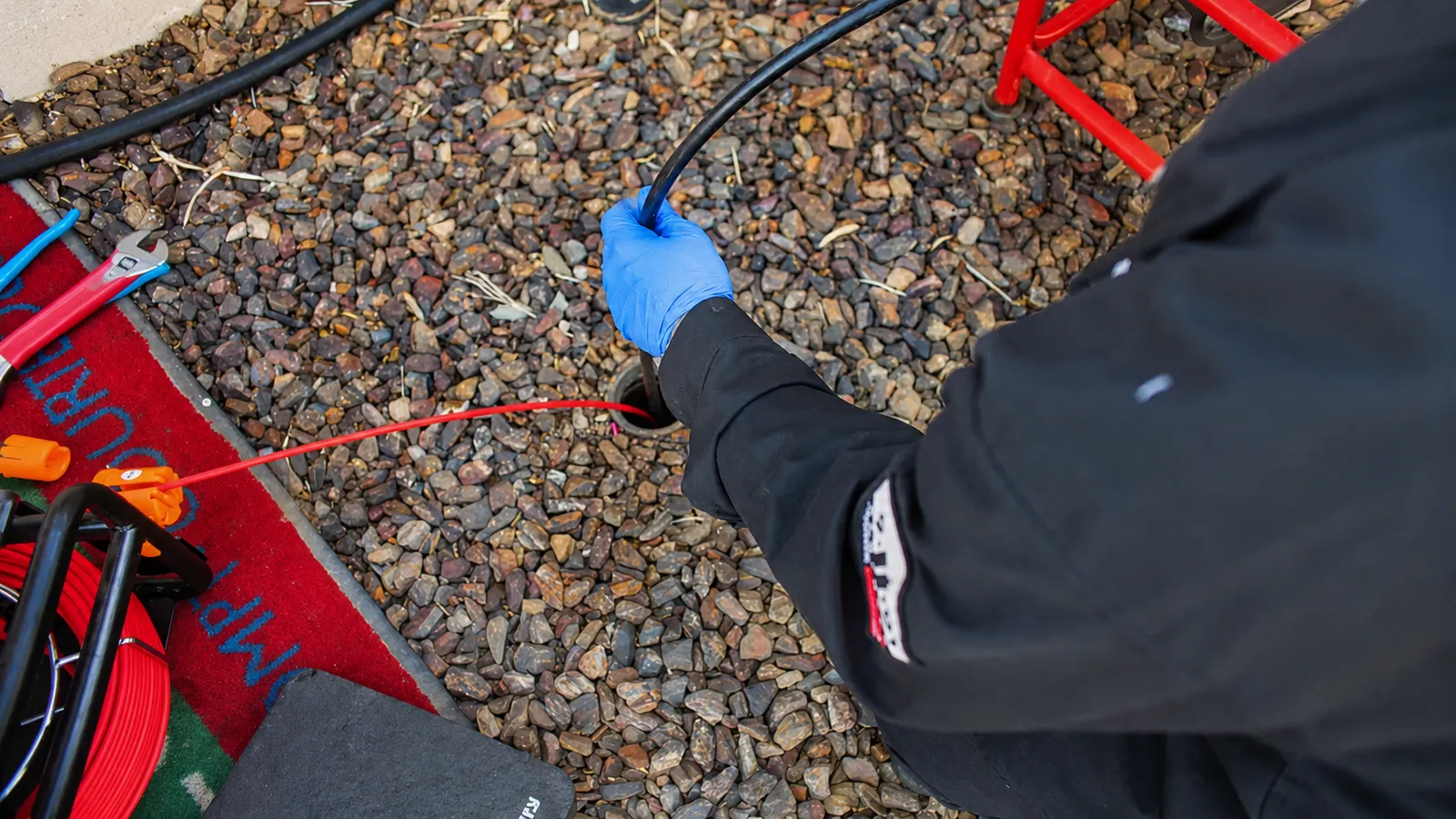 Now Plumbing technician feeding a camera line into a drain cleanout